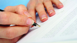 two hands, right hand writing on paper